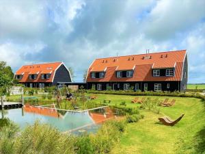 a large building with an orange roof next to a lake at Grand Villa with Sauna & Jacuzzi in Den Burg