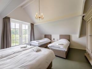 a bedroom with two beds and a chandelier at Achterhoek Estate with Private Pool in Aalten +18 photos