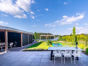 a patio with a table and chairs and a yard at Water Villa, Sauna & Beach in Sibculo