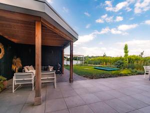a covered patio with a bed and chairs on it at Water Villa, Sauna & Beach in Sibculo
