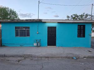 a blue building with a black door in a street at Mi casa in Ciudad Juárez