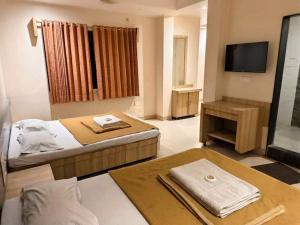 a hotel room with a bed and a television at Blueberry Budget Hotel in Shirdi +36 photos