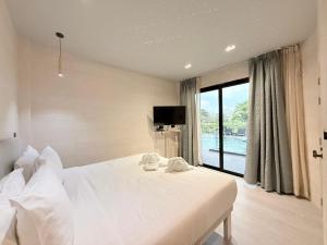 ein Schlafzimmer mit einem weißen Bett und einem großen Fenster in der Unterkunft Little Loft Hotel in Phuket + 40 Fotos