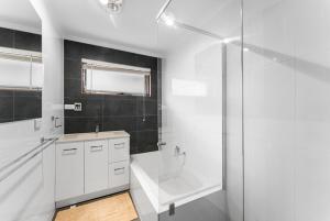 a white bathroom with a sink and a shower at Private 4BR Garden Haven - Spacious & Serene in Mawson Lakes +7 photos