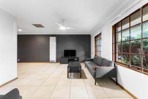 a living room with a couch and a tv at Private 4BR Garden Haven - Spacious & Serene in Mawson Lakes