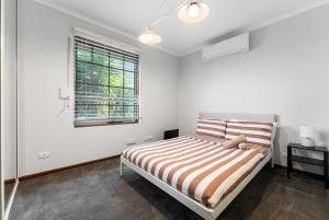 a white bedroom with a bed and a window at Private 4BR Garden Haven - Spacious & Serene in Mawson Lakes