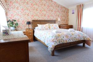 a bedroom with a bed and floral wallpaper at La Casa in Napier