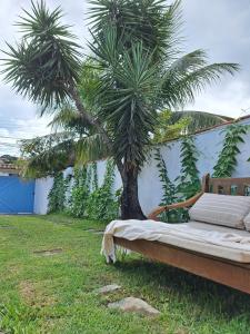 a bed sitting in the grass next to a palm tree at El refugio in Búzios