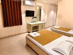 a hotel room with two beds and a television at Blueberry Budget Hotel in Shirdi