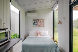 a small bedroom with a bed and a window at Deloraine Tiny Retreat by Tiny Away in Whangarei