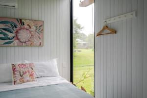 a bedroom with a bed and a large window at Deloraine Tiny Retreat by Tiny Away in Whangarei