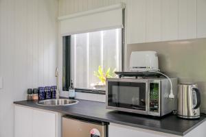 a kitchen counter with a microwave and a sink at Deloraine Tiny Retreat by Tiny Away in Whangarei