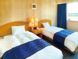 a hotel room with two beds and a window at Hotel Grand Plaza Urashima in Kurihara