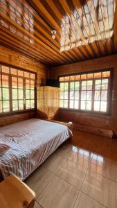 a bedroom with a bed in a room with windows at CABAÑA RaNCH OXAPAMPA in Oxapampa