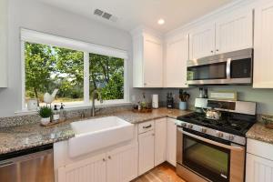 a kitchen with white cabinets and a sink and a window at Vineyard Setting With 180 Panoramic Lake Views in Lower Lake