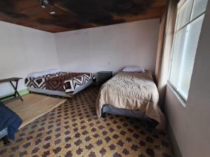 two beds sitting in a room with a window at La Casa del Barrio in Quetzaltenango