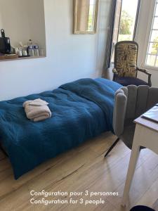 a bed with a blue blanket in a room at La Villa Mirabelle 2min d'Arromanches-les-Bains in Tracy-sur-Mer