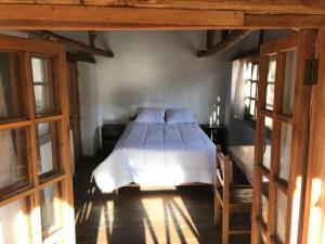 a bedroom with a bed in a room with windows at Los Laureles Sacred valley in Urubamba