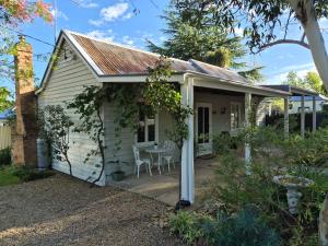 a small white house with a table and chairs at Finchy Cottage in Beechworth