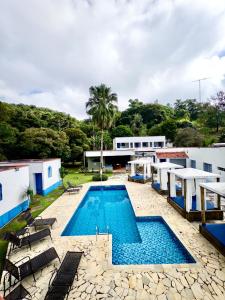 a large swimming pool with chairs and a building at Pousada Santorini Guararema in Guararema