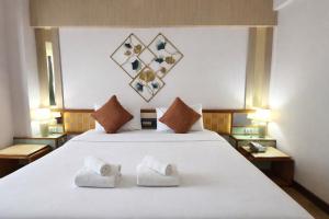 ein Schlafzimmer mit einem großen weißen Bett mit zwei Handtüchern in der Unterkunft Asian Hotel in Hat Yai