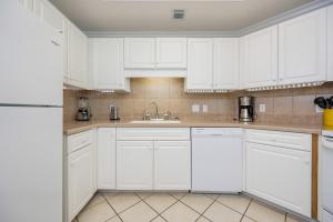 a white kitchen with white cabinets and a sink at Phoenix on the Bay 1409 condo in Orange Beach