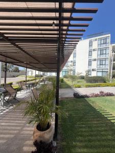 a wooden pergola with a potted plant under it at Gran departamento con alberca, terraza y vista a lago en Lago Luna - 5 minutos de Chante Spa in Chantepec