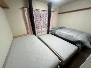 two beds in a small room with a window at 旭川ロキ in Asahikawa