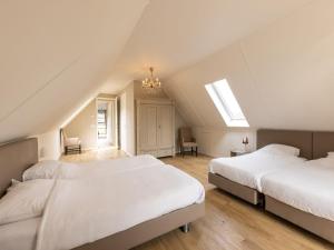 a attic bedroom with two beds and a chandelier at Achterhoek Villa with Heated Pool in Aalten +26 photos