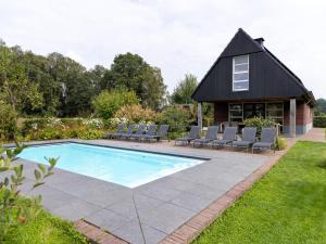 a swimming pool with chairs and a house at Achterhoek Villa with Heated Pool in Aalten