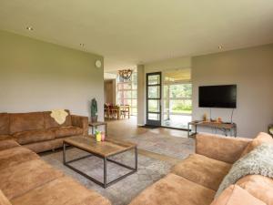 a living room with a couch and a tv at Achterhoek Villa with Heated Pool in Aalten