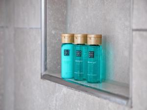 three blue bottles on a shelf in a bathroom at Stylish Texel Escape with Spa in Den Burg