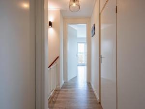 a hallway with white walls and a door and wooden floors at Stylish Texel Escape with Spa in Den Burg