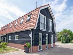 a black house with a red roof at Stylish Texel Escape with Spa in Den Burg +122 photos