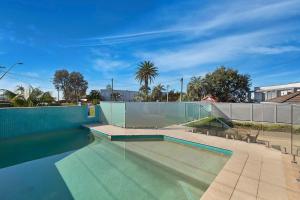 an empty swimming pool with a fence and a blue at Ocean Pines Apartment 5 in The Entrance