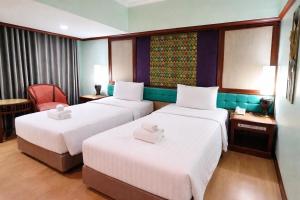 ein Hotelzimmer mit zwei Betten und einem Stuhl in der Unterkunft Asian Hotel in Hat Yai
