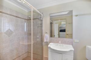 a white bathroom with a sink and a shower at Bluewater at Mannering Park in Mannering Park +12 photos