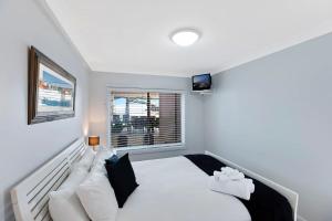 a bedroom with a white bed and a window at Ocean Pines Apartments 4 in The Entrance