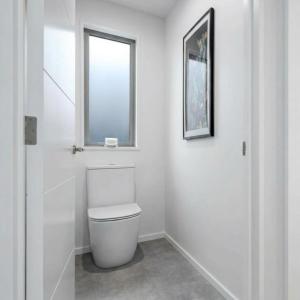 a white bathroom with a toilet and a window at Mount Pisa View Stay - Barnd new holiday home in Cromwell +3 photos