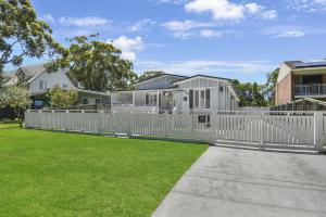 a white picket fence in front of a house at Margaret's Hamptons Beach House in Hawks Nest