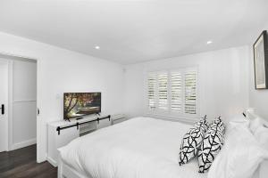 a white bedroom with a white bed and a window at Margaret's Hamptons Beach House in Hawks Nest