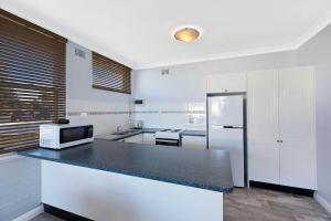 a kitchen with a black counter top and a refrigerator at Golden Sands Apartment 10 in The Entrance
