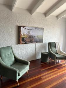 a living room with two chairs and a car on the wall at The Sage Sea Shack in Caloundra