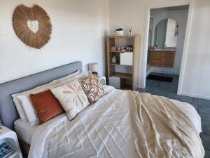 a bedroom with a bed with pillows and a mirror at Ocean View Oasis in Cannonvale