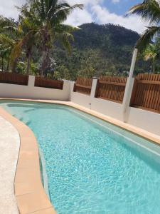 a swimming pool next to a resort with palm trees at Ocean View Oasis in Cannonvale