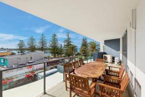 a balcony with a wooden table and chairs at Coast Apartments 19 Roof Top Pool in The Entrance