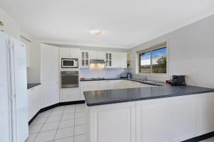 a kitchen with white cabinets and a black counter top at Bonnieview House in Shelly Beach +2 photos