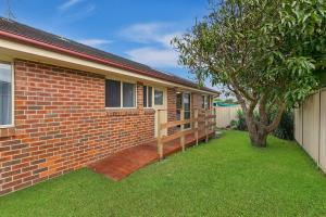 a brick house with a porch and a tree at Bonnieview House in Shelly Beach