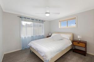 a white bedroom with a bed and a window at Bonnieview House in Shelly Beach