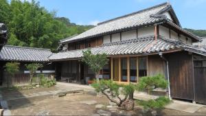 an asian style house with a garden in front of it at 尾上邸 日本遺産の一棟貸し 離島の宿 in Marugame